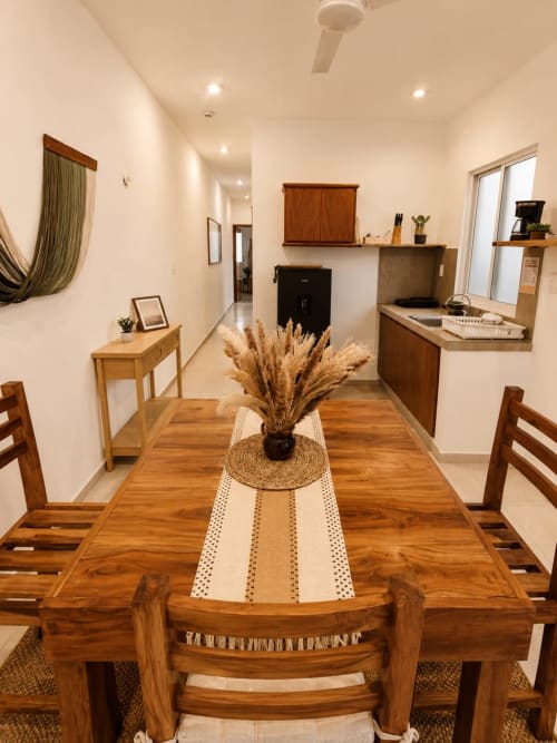 Comedor moderno en suite del Hotel Isla Mujeres Centro con mesa de madera, sillas y centro de mesa con pampas