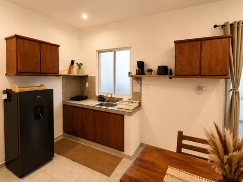 Moderno kitchenette en suite del Hotel Isla Mujeres con muebles de madera, refrigerador negro y vistas al océano
