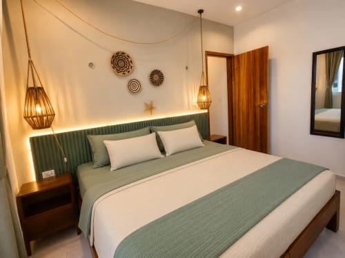 Habitación moderna del Hotel Isla Mujeres Centro con cabecera verde, muebles de madera e iluminación ambiente con lámparas colgantes en Isla Mujeres