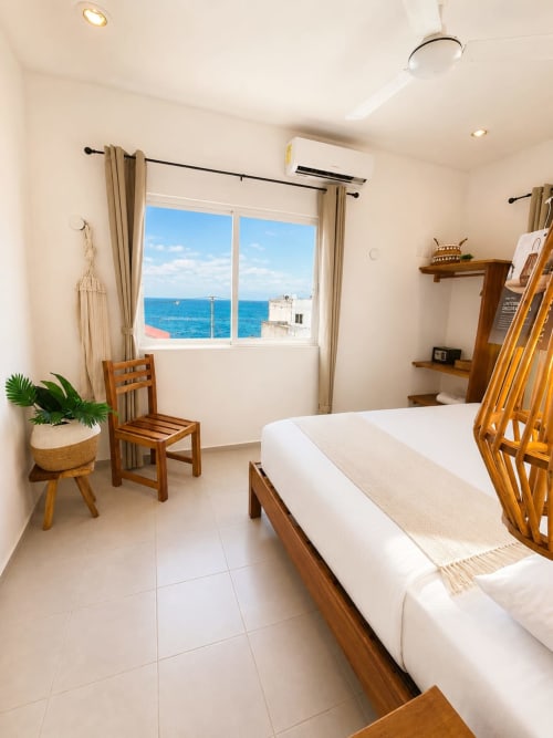 Habitación luminosa frente al mar en Hotel Isla Mujeres Centro con vista oceánica, muebles de madera y ropa de cama blanca