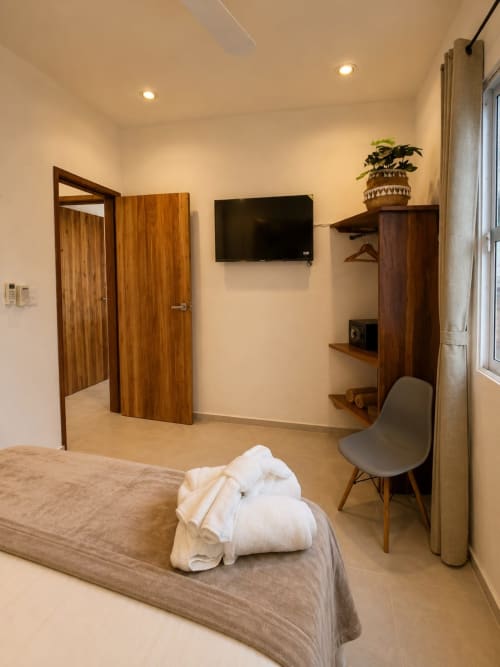 Habitación moderna del Hotel Isla Mujeres Centro con cama, televisor, muebles de madera y ventana con vista al océano