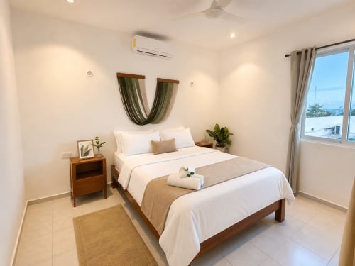 Dormitorio moderno y luminoso en Hotel Isla Mujeres Centro con cama queen, mesita de noche de madera, vistas al mar y decoración costera