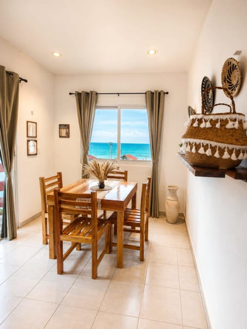 Comedor luminoso con vista al océano en Hotel Isla Mujeres Centro, mesa y sillas de madera, decoración costera