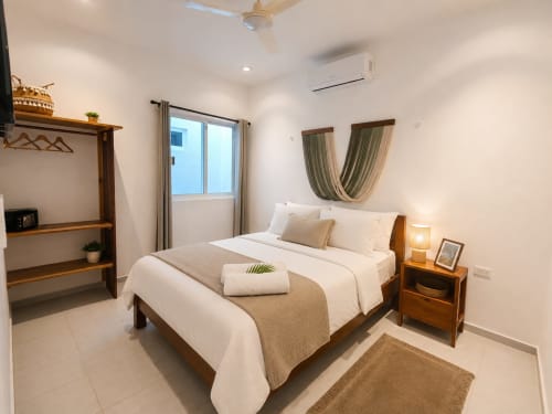 Dormitorio moderno en Hotel Isla Mujeres Centro con cama de madera, ropa blanca, ventana con vista al mar y mobiliario contemporáneo