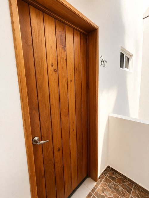 Entrada de la Suite 17 en Hotel Isla Mujeres Centro con puerta de madera y piso de baldosas de piedra en pasillo