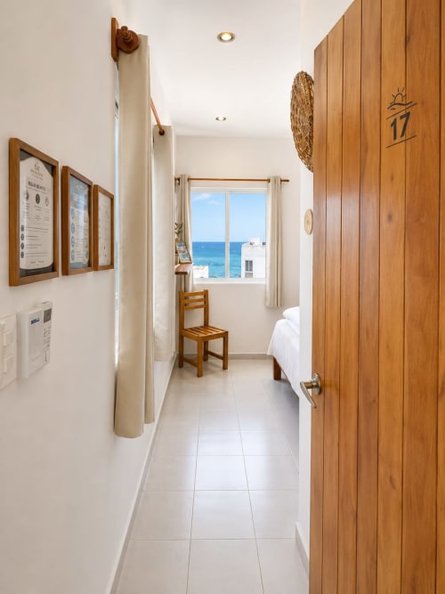 Pasillo de la Suite 17 en Hotel Isla Mujeres Centro con puerta de madera, ventana con vista al mar y luminoso ambiente costero