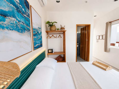 Habitación moderna de hotel frente al mar con camas gemelas, cabecero turquesa y vistas al arte marino en Hotel Isla Mujeres