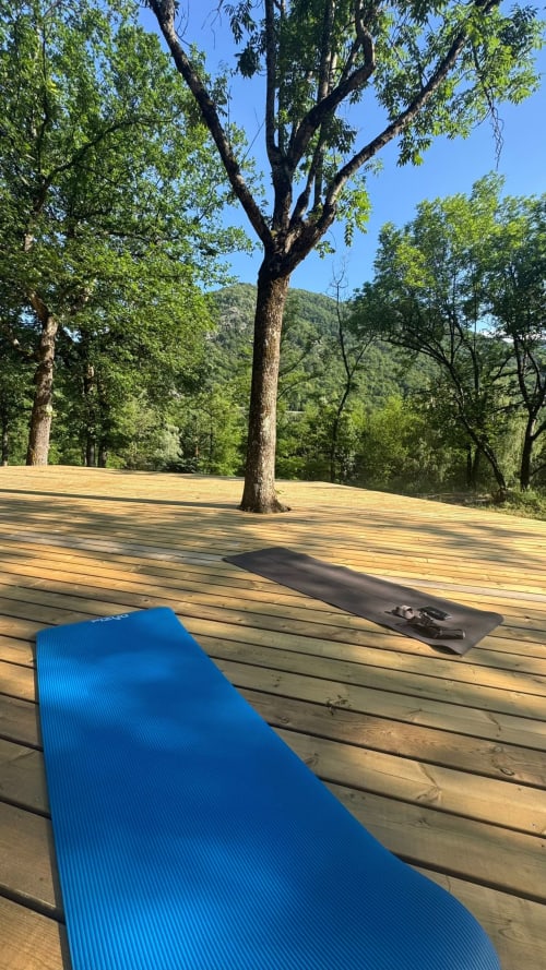 Tapis de yoga bleu sur terrasse en bois avec vue sur les sapins et les montagnes aux Hauts d'En Castel, Ax-les-Thermes