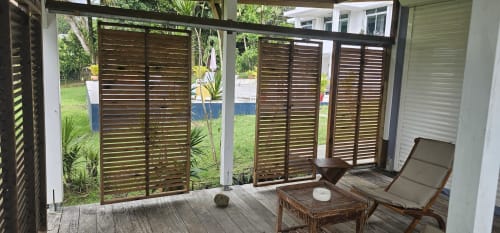 Terrasse couverte aux portes persiennées en bois ouvrant sur le jardin de la villa Les Cassias à Petit Bourg