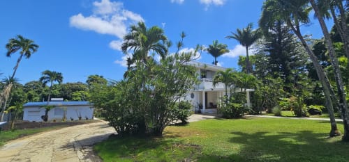 Villa Les Cassias B&B in Petit Bourg, Guadeloupe mit weißem Haus, Palmen und üppigen tropischen Gärten.