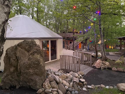 Modern glamping tent with wooden deck at Les Murmures du Bois, Sousceyrac-en-Quercy, surrounded by forest and colorful lights