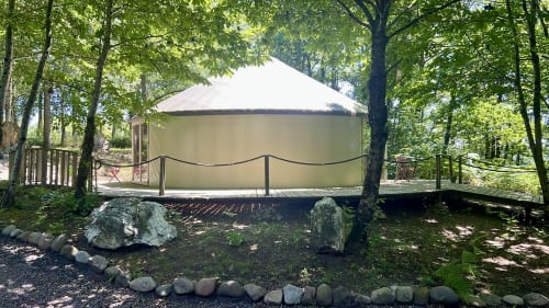 Glamping tent nestled in forest at Les Murmures du Bois, Sousceyrac-en-Quercy, with wooden deck and garden surroundings