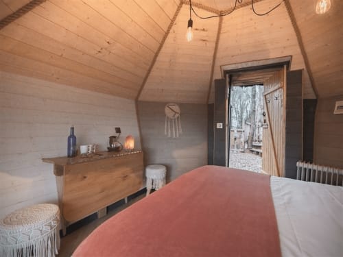 Chambre douillette au gîte Les Murmures du Bois avec meubles en bois, lit corail et porte-fenêtre sur le jardin