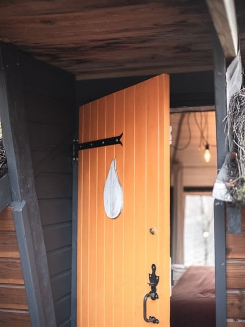 Élégante porte d'entrée en bois avec panneaux orange et fenêtre en forme de larme blanche, chambre avec vue sur le jardin Les Murmures du Bois