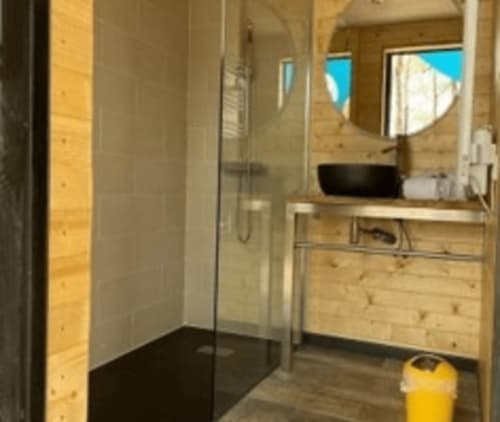 Salle de bain moderne aux Murmures du Bois avec douche à l'italienne, vasque et accents de bois naturel dans la chambre Nuit dorée