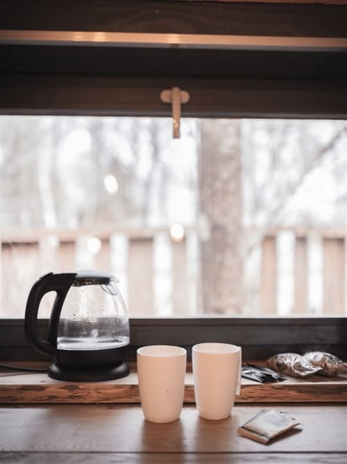 Café aux Murmures du Bois avec carafe, tasses et pâtisseries surplombant la vue sur le jardin