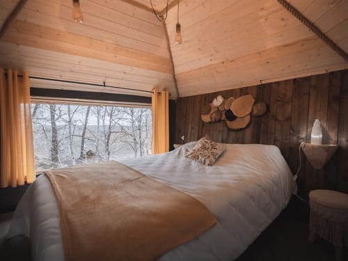 Chambre cosy en bois aux Murmures du Bois avec lit, vue sur la forêt et décoration murale en bois