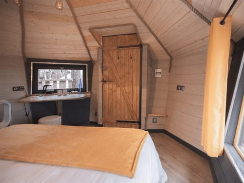 Chambre cosy de la suite Nuit dorée aux Murmures du Bois avec lit, bureau, armoire en bois et vue sur le jardin