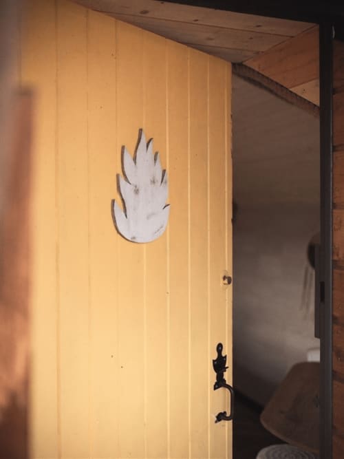 Porte en bois jaune avec élément décoratif blanc flammé aux Murmures du Bois B&B, chambre Nuit dorée
