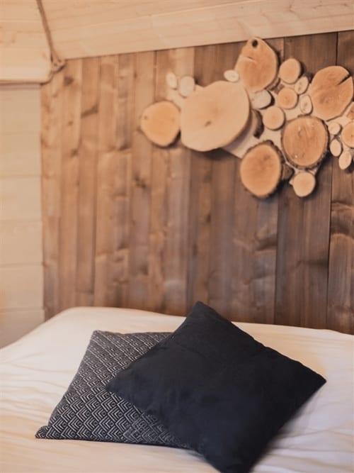 Bedroom at Les Murmures du Bois with wooden headboard, wall art, and pillows on white bedding