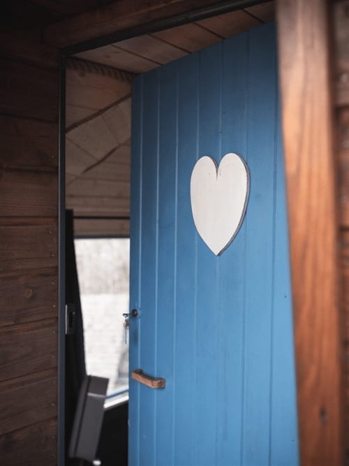 Blue wooden door with white heart cutout at Les Murmures du Bois Nuit céleste room