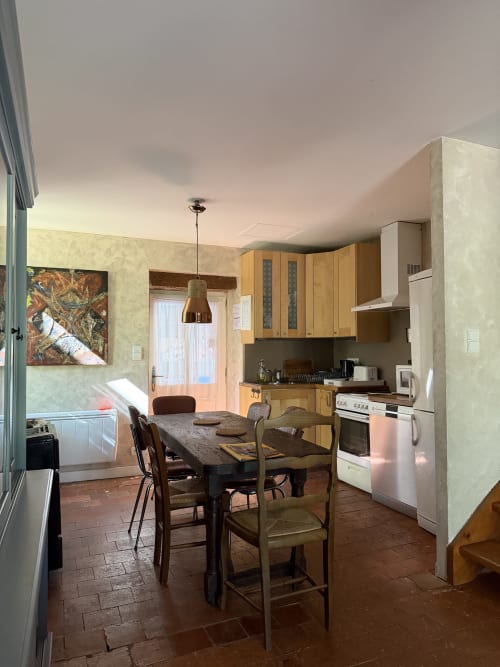 Cottage kitchen and dining area at Domaine les Bertrands with wooden cabinets, dining table, and garden view
