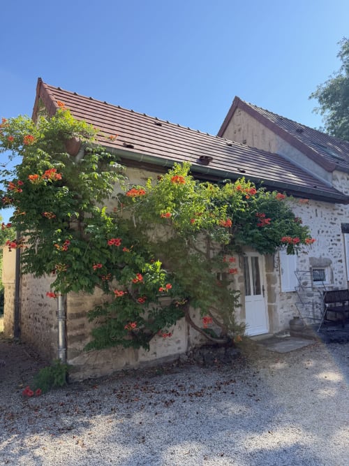 Maison en pierre avec fleurs rouges au Domaine les Bertrands, Couches, France - vue sur le jardin