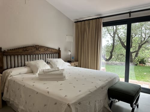 Dormitorio luminoso en El Escondite De Pedro Malillo de Candeleda con cabecero de madera, ropa de cama crema y vistas al jardín