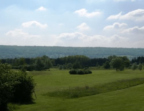 Scenic green valley landscape near La Roche Guyon with rolling hills, forest, and cloudy sky at Le Paradis de Lucile