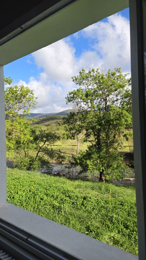 View from Mas le Châtelet hotel window showing Pyrenees landscape with green valley and stream in Saint-Paul-de-Fenouillet