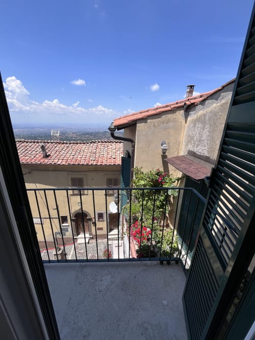 Vista dal balcone di Cuore di Rocca a Rocca di Papa: tetti rossi, fiori e il panoramico paesaggio dei Castelli Romani