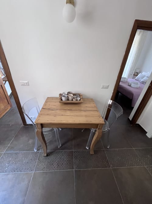 Tavolo da pranzo in legno con sedie trasparenti nell'appartamento Piazza Vecchia dell'hotel Cuore di Rocca a Rocca di Papa