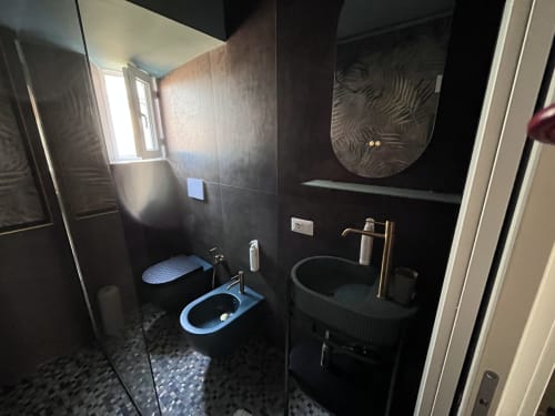 Bagno moderno nero con wc blu, lavabo rotondo e rubinetto in ottone all'hotel Cuore di Rocca a Rocca di Papa