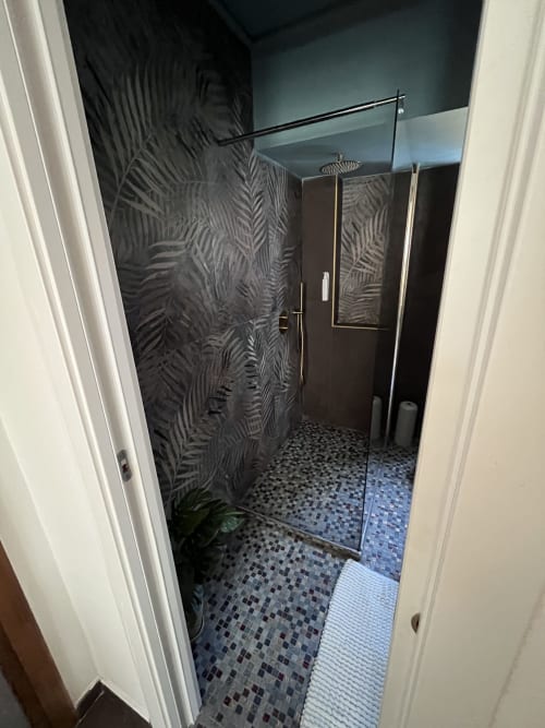 Bagno moderno con doccia a filo parete, piastrelle nere a tema felce e soffione a cascata all'hotel Cuore di Rocca a Rocca di Papa