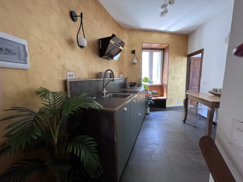 Cucina moderna con mobili neri, lavello in acciaio inossidabile e pareti texture color ocra presso Cuore di Rocca a Rocca di Papa