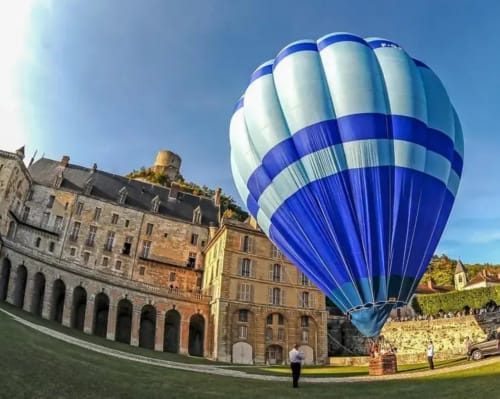 Blue and white hot air balloon above historic château at Le Paradis de Lucile, La Roche Guyon