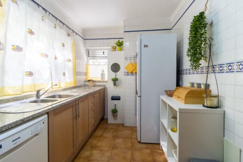 Cocina moderna en apartamento de Portimão con muebles de madera, electrodomésticos blancos y detalles de azulejos azules