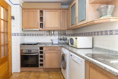 Cocina moderna con gabinetes de madera, encimeras de granito y electrodomésticos en Apartamento Marina Galé, Portimão