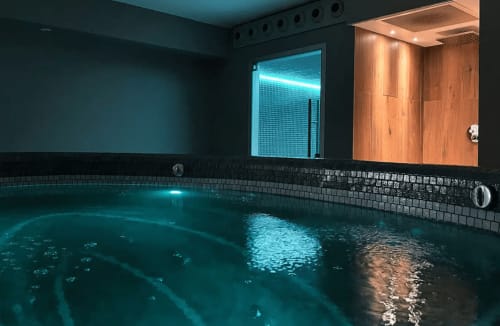 Piscine intérieure moderne aux eaux turquoise et carrelage noir au gîte Le Paradis de Lucile à La Roche Guyon