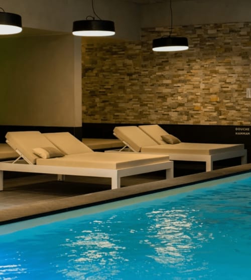 Espace piscine moderne au Paradis de Lucile avec transats, luminaires suspendus et mur de briques à La Roche Guyon