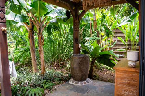 Entrée de cottage tropical aux Indes Occidentales avec bananiers luxuriants, fontaine en pierre et terrasse en bois panoramique