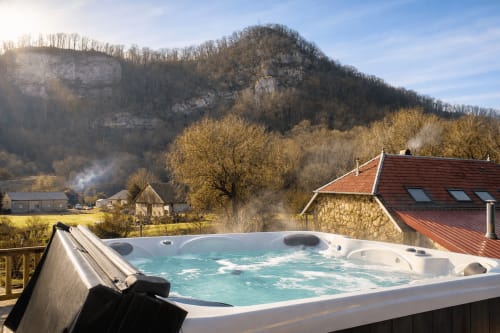 Bain à remous avec vue sur la vallée de la Cusance à l'Auberge La Source Bleue, falaises calcaires et bâtisses françaises traditionnelles.