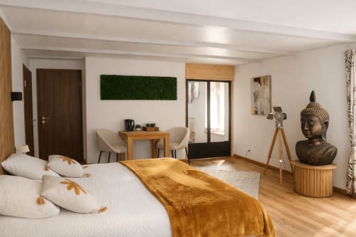 Suite luxueuse avec vue sur jardin à l'Auberge La Source Bleue, lit en bois avec plaid doré et décor moderne