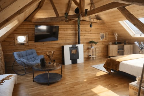 Suite scandinave à La Source Bleue à Cusance avec poutres en bois, cheminée, téléviseur, fauteuil bleu et lit