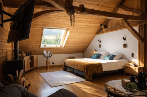 Suite scandinave à La Source Bleue avec poutres apparentes, puits de lumière, lit aux oreillers bleus et vue sur les montagnes de Cusance