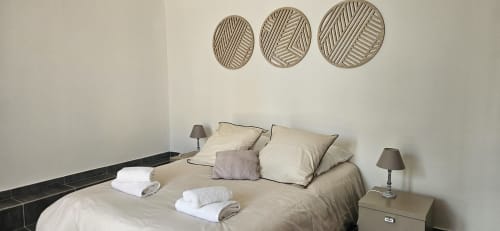 Chambre lumineuse à Mi Casa Es Su Casa avec parure de lit crème, assiettes décoratives murales et lampes de chevet à Villemoustaussou