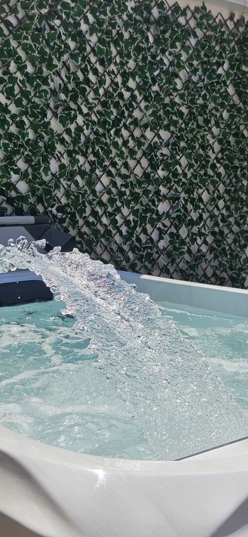 De l'eau pétillante versée dans un jacuzzi turquoise avec un mur de lierre verdoyant à l'appartement Mi Casa Es Su Casa