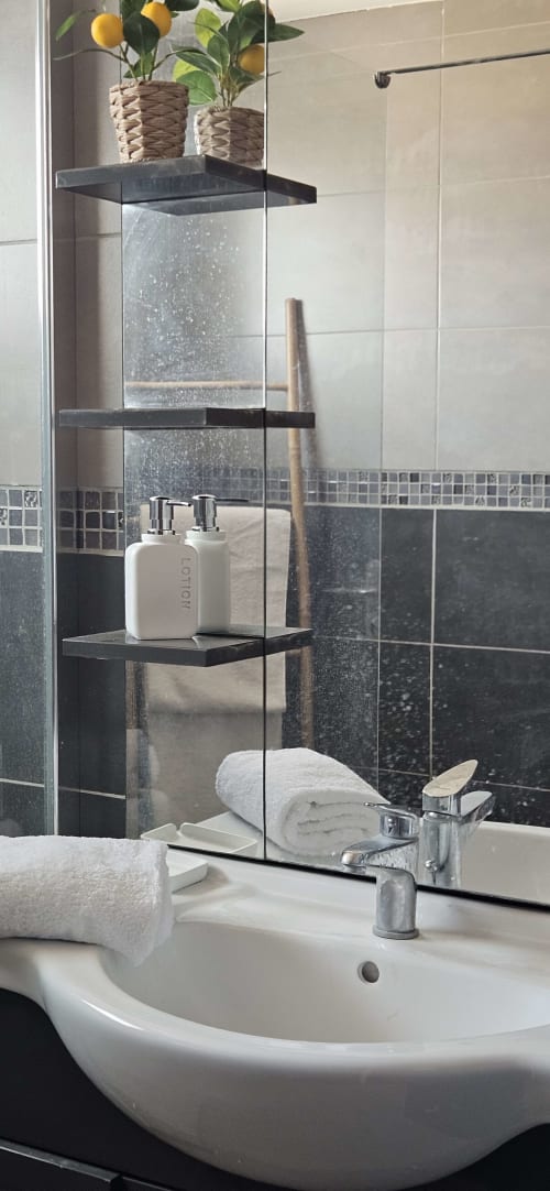 Lavabo moderne de la salle de bain avec serviettes blanches et articles de toilette dans l'appartement Le Loft à Mi Casa Es Su Casa, Villemoustaussou