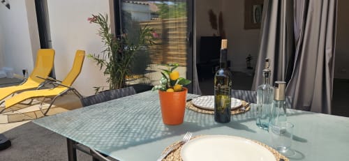 Terrasse extérieure de Mi Casa Es Su Casa à Villemoustaussou avec transats jaunes, plantes en pots, couverts et