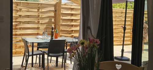 Élégante terrasse de restaurant chez Mi Casa Es Su Casa avec clôture de bois, chaises noires, fleurs et vue sur le jardin
